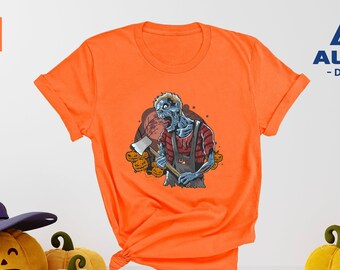 May include: Orange t-shirt with a graphic of a zombie holding an axe. The zombie is wearing a plaid shirt and overalls. The graphic is surrounded by pumpkins. The t-shirt is on a white background. "ALPINE - DESIGN -" is printed on the top right corner of the image.