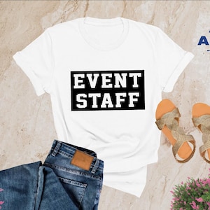 May include: White t-shirt with black text that says "EVENT STAFF" in a bold, blocky font.