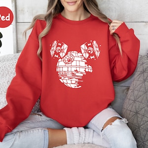 May include: Red sweatshirt with a white graphic of a Death Star from Star Wars with two TIE fighters on either side of it.