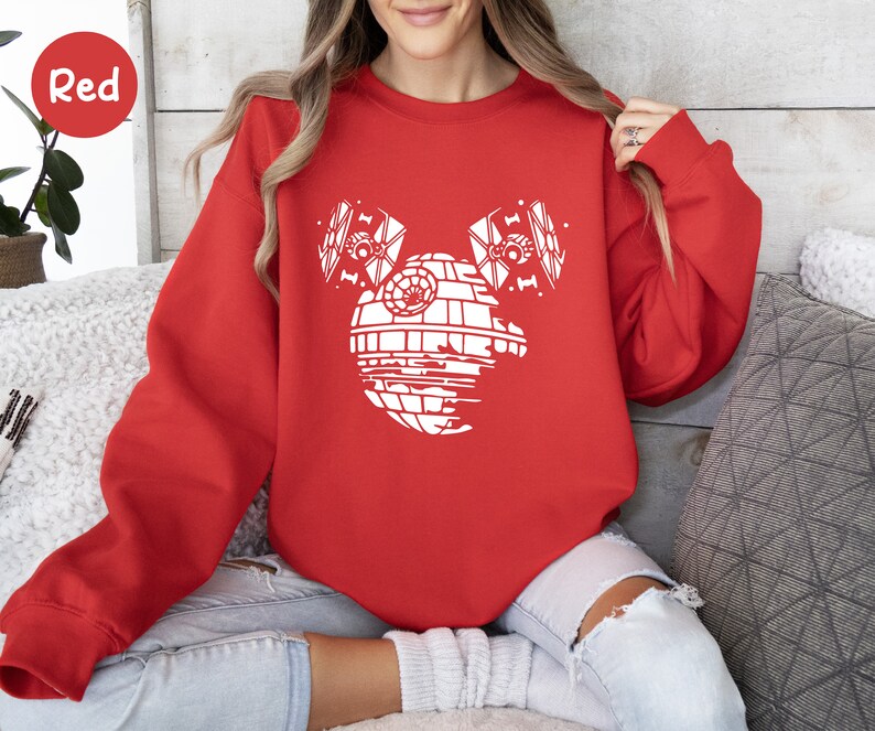May include: Red sweatshirt with a white graphic of a Death Star from Star Wars with two TIE fighters on either side of it.