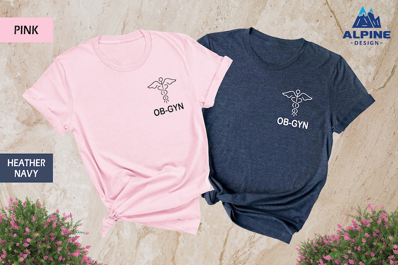 May include: Two t-shirts, one pink and one heather navy, with a medical caduceus symbol and the text "OB-GYN" printed on the front.