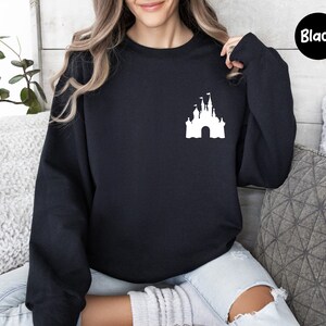 Op de afbeelding: Een zwart sweatshirt met een wit silhouet van Assepoester's kasteel op de voorkant. Het sweatshirt is een ronde hals en heeft lange mouwen.
