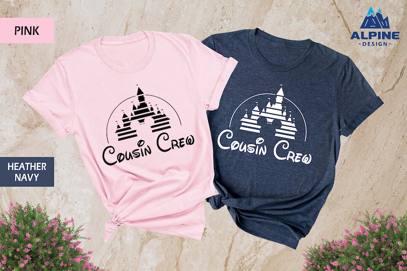 Pode incluir: Duas camisetas com um gr&aacute;fico preto e branco de um castelo com o texto "Cousin Crew" em uma fonte de escrita cursiva preto e branco. As camisetas s&atilde;o rosa e azul marinho mesclado.