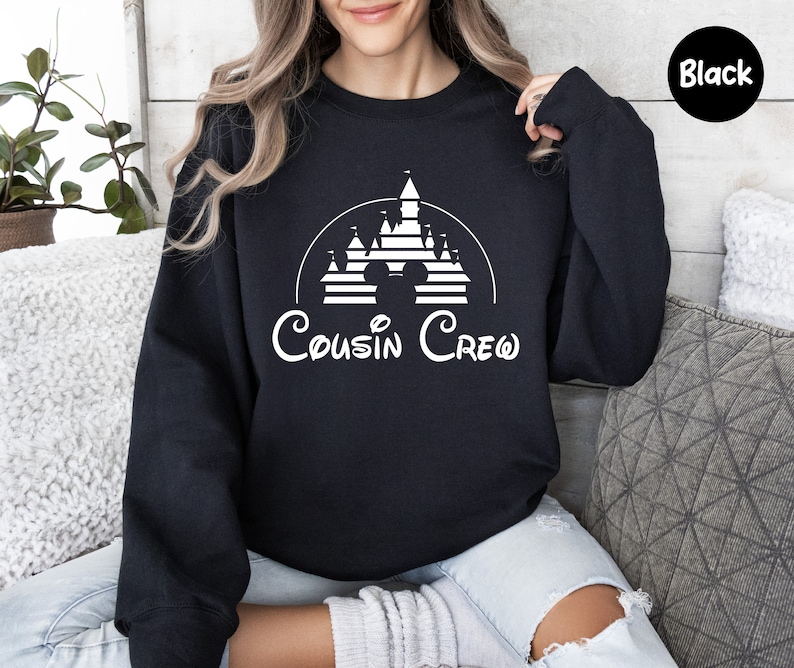 Pode incluir: Camisola de cor preta com um gr&aacute;fico branco de um castelo da Disney e o texto "Cousin Crew".