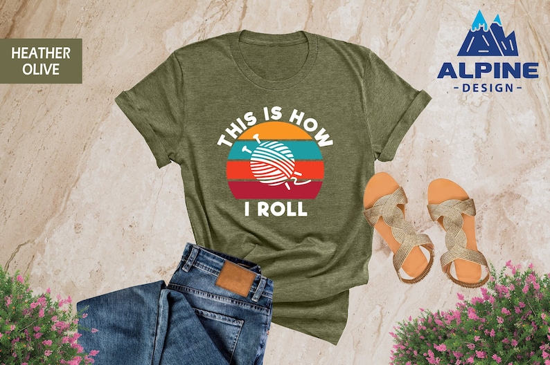 May include: A green t-shirt with a retro sunset graphic and the text "This is how I roll" with a yarn ball and knitting needles in the center of the sunset.