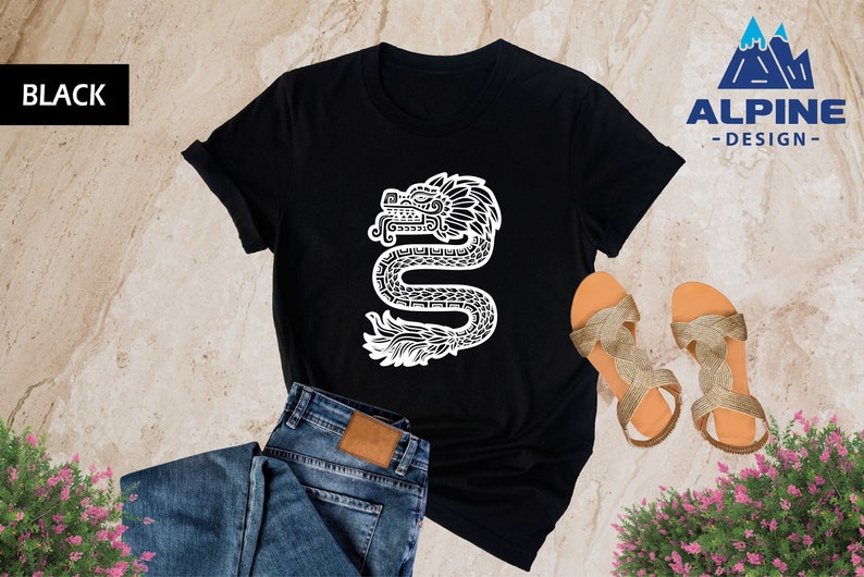 Może przedstawiać: Czarny T-shirt z białym nadrukiem stylizowanej węża z pi&oacute;ropuszem. Tekst "ALPINE -DESIGN- " znajduje się w prawym g&oacute;rnym rogu obrazu.