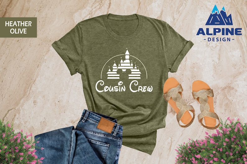 Pode incluir: Uma camiseta verde oliva heather com um gr&aacute;fico branco de um castelo e o texto "Cousin Crew".
