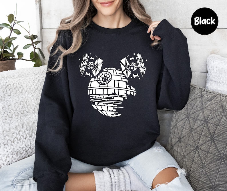 May include: Black sweatshirt with a white graphic of the Death Star from Star Wars, with two TIE fighters on either side of the Death Star, forming a Mickey Mouse silhouette.