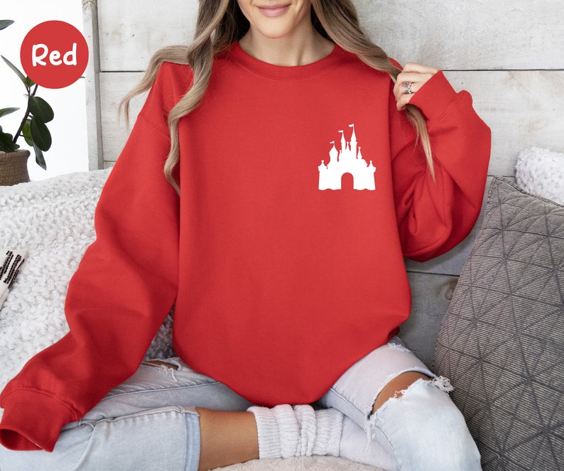 Op de afbeelding: Rood sweatshirt met een wit silhouet van Assepoester's kasteel op de voorkant.