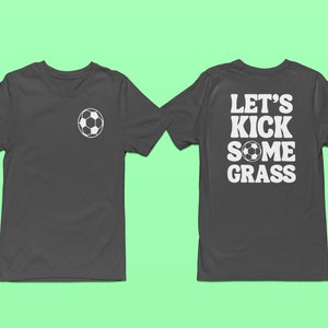 Op de afbeelding: Een donkergrijs T-shirt met een witte voetbalafbeelding aan de voorkant en de tekst "Let's Kick Some Grass" met een witte voetbalafbeelding aan de achterkant.