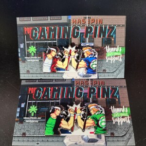 May include: Two enamel pins featuring a retro video game style design of two characters fighting. The pins are on a card with the text "HASSPIN GAMING PINZ" and "thanks for your support".
