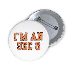 May include: White button with orange text that reads "I'M AN SEC 8".
