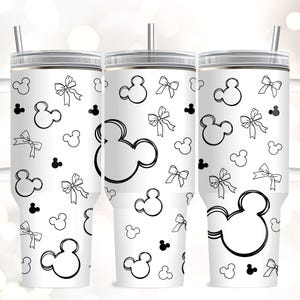 May include: White tumbler with a handle, lid, and straw, featuring a black and white pattern of Mickey Mouse heads, bows, and small Mickey Mouse silhouettes. The tumbler is designed for cold beverages.