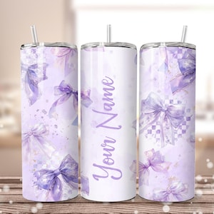 Op de afbeelding: Drie roestvrijstalen bekers met deksels en rietjes. De bekers hebben een aquarelontwerp van paarse strikken en spetters op een witte achtergrond. De middelste beker heeft de tekst "Your Name" in paars schrift.