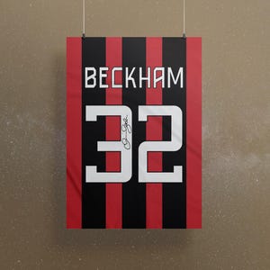 Pode incluir: Uma camisa listrada vermelha e preta com o nome "Beckham" e o número "32" em branco. O número tem uma assinatura em tinta preta.