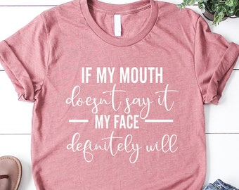 May include: A pink t-shirt with the text "If my mouth doesn't say it - my face definitely will" in white lettering.