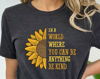 May include: A dark grey t-shirt with a sunflower graphic and the text "In a world where you can be anything be kind".