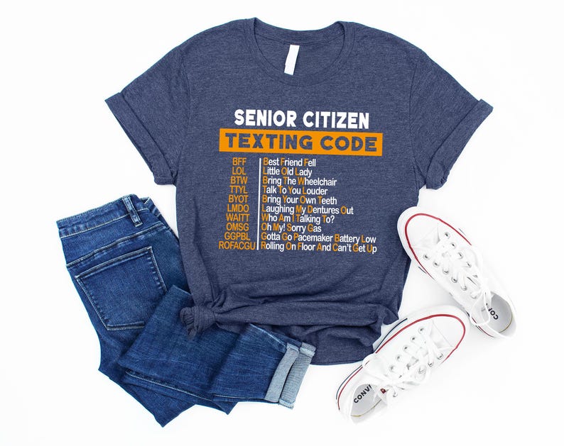 Pu&ograve; includere: Una maglietta blu navy con una grafica bianca che dice "Senior Citizen Texting Code" e elenca le comuni abbreviazioni di messaggi di testo degli anziani e i loro significati in testo arancione.