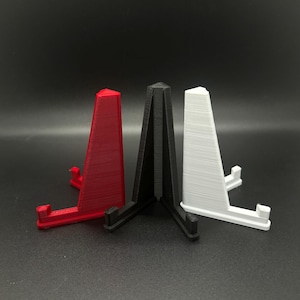 May include: Three triangular display stands made of plastic. The stands are red, black, and white.