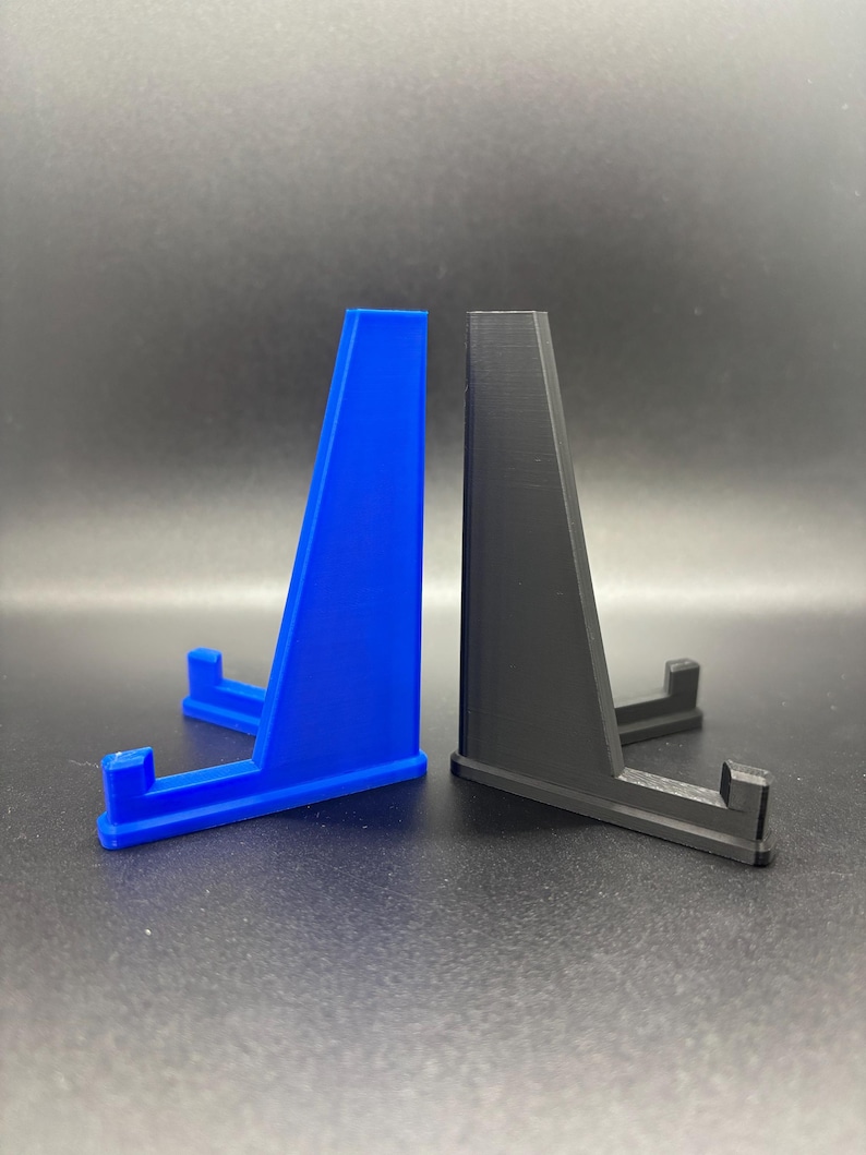 May include: Two display stands, one blue and one black, made of plastic. The stands are shaped like a triangle with a small platform at the top.