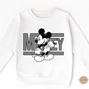 May include: White sweatshirt with a black and white graphic of Mickey Mouse and the word "Mickey" printed on it.