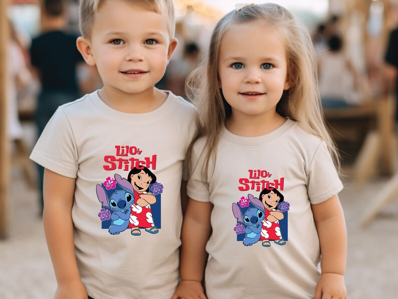 May include: Two children wearing beige t-shirts with a graphic of Lilo and Stitch from the Disney movie. The shirts feature the text "Lilo & Stitch" in red and blue.