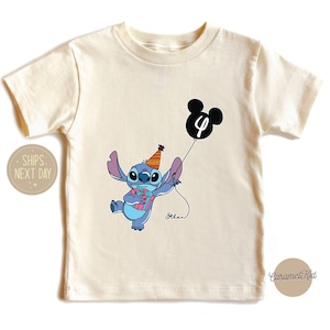 May include: A white t-shirt with a blue Stitch character holding a balloon with the number 4 on it. The balloon is shaped like Mickey Mouse's head. The shirt has a light blue and pink design on the character.