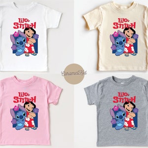 May include: Four different colored t-shirts featuring a cartoon image of Lilo and Stitch from the Disney movie Lilo & Stitch. The shirts are white, beige, pink, and gray.