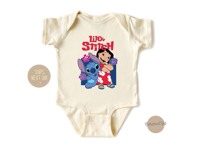 May include: A cream-colored baby onesie with a graphic of Lilo and Stitch from the Disney movie Lilo & Stitch. The text "Lilo & Stitch" is printed in red letters above the characters.