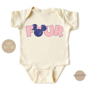K&ouml;nnte beinhalten: Ein wei&szlig;er Baby-Body mit einer pinkfarbenen und blauen Grafik, auf der "FOUR" steht, mit einem blauen Mickey-Maus-Kopf mit einer pinkfarbenen Schleife oben drauf.