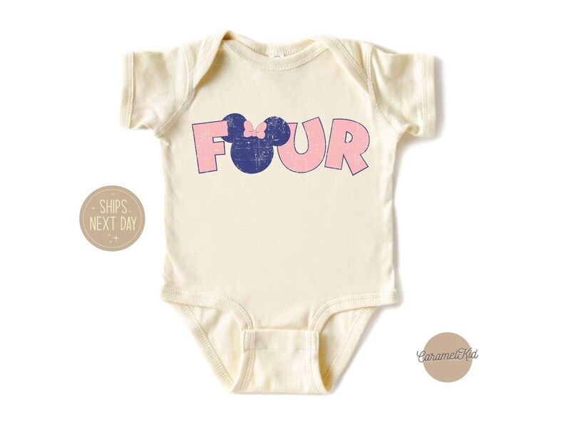 K&ouml;nnte beinhalten: Ein wei&szlig;er Baby-Body mit einer pinkfarbenen und blauen Grafik, auf der "FOUR" steht, mit einem blauen Mickey-Maus-Kopf mit einer pinkfarbenen Schleife oben drauf.