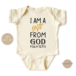 Op de afbeelding: Een cr&egrave;mekleurige baby romper met de tekst "I AM A gift FROM GOD PSALM 127:3" in zwarte en gouden letters.