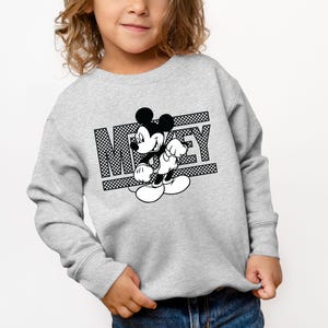 May include: A gray sweatshirt with a black and white graphic of Mickey Mouse and the word "Mickey" printed on it.