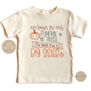 May include: Cream-colored toddler t-shirt with the text "no longer the only PUMPKIN IN THE PATCH. I'm going to be a BIG SISTER." The design includes orange and green pumpkin graphics, perfect for an announcement.