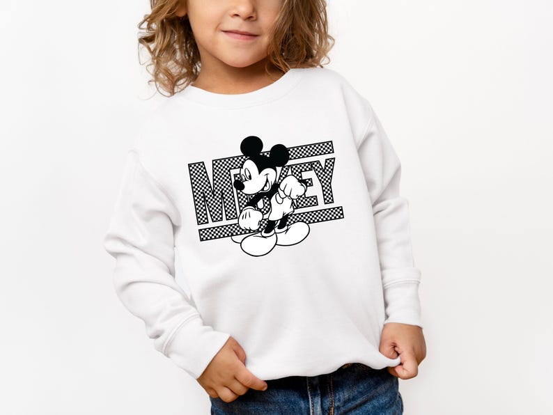 May include: White sweatshirt with a black and white graphic of Mickey Mouse and the word "Mickey" printed on it.