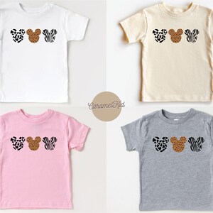 May include: Four toddler-sized t-shirts in different colors with a print of three Mickey Mouse heads in different animal prints. The prints are leopard, cheetah, and zebra.