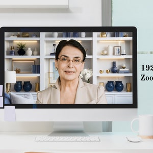 May include: A woman on a video call on a computer monitor. The monitor is on a white desk with a white mug, a camera, and books. The text on the monitor reads "Full HD 1920 x 1080 px Zoom Optimized."