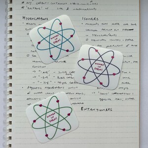 May include: Three colorful stickers with a green, blue, and red atom design. Each sticker has the text "Women in STEM!" in pink letters.