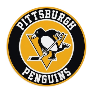 May include: A black and gold circular logo with the text "Pittsburgh Penguins" in white. A black and white penguin is holding a hockey stick and skating on a yellow triangle.