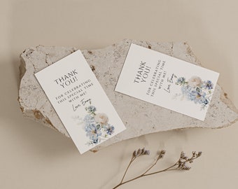 Op de afbeelding: Twee witte bedankkaartjes met blauwe en witte bloemenmotieven. De tekst op de kaartjes luidt "Bedankt! Voor het vieren van deze speciale tijd met mij! Liefs, Emma".