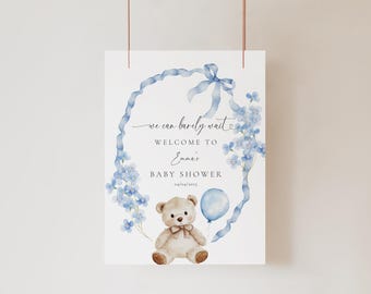 Puede incluir: Un cartel de bienvenida para un baby shower azul y blanco con un osito de peluche sosteniendo un globo azul. El cartel dice "We can barely wait, Welcome to Emma's Baby Shower".