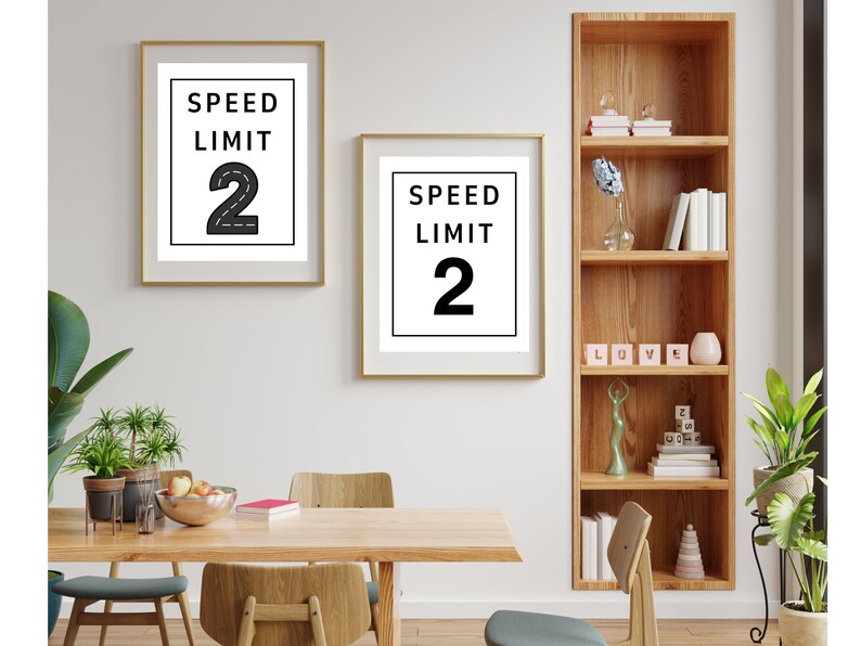 Puede incluir: Dos impresiones enmarcadas en blanco y negro con el texto "Speed Limit 2" sobre un fondo blanco. Las impresiones est&aacute;n colgadas en una pared blanca sobre una mesa de madera con sillas.