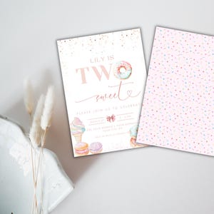 Op de afbeelding: Roze en witte verjaardagsuitnodiging met de tekst "Lily is Two Sweet" en een donut, een ijshoorn en macarons. De achtergrond is een roze en wit spikkels patroon.