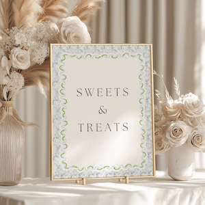 Puede incluir: Un cartel con marco dorado, fondo blanco y borde de acuarela azul y verde. El cartel dice "SWEETS & TREATS" en texto negro.