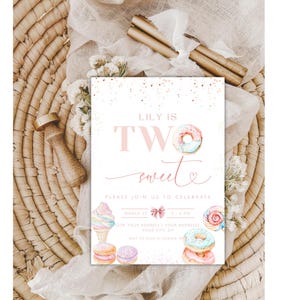 Op de afbeelding: Een roze en witte uitnodigingskaart met de tekst "Lily is Two Sweet" en een aquarel-illustratie van donuts, ijs en macarons. De kaart is versierd met gouden glitter.