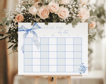 May include: A white calendar with a blue ribbon and floral accents. The calendar is titled "Guess the due date" and has the days of the week labeled S, M, T, W, T, F, S.