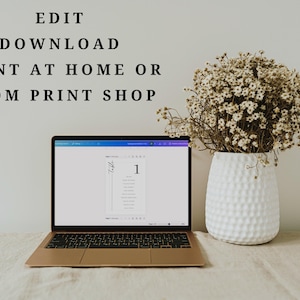 May include: A laptop displaying a digital table number template on its screen, positioned next to a white textured vase filled with dried baby's breath flowers. The text "EDIT DOWNLOAD PRINT AT HOME OR FROM PRINT SHOP" is visible above the laptop.