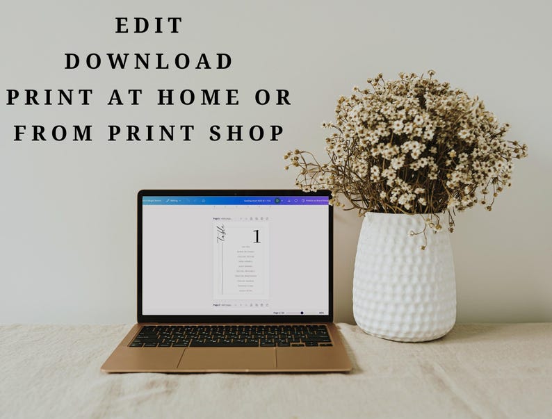 May include: A laptop displaying a digital table number template on its screen, positioned next to a white textured vase filled with dried baby's breath flowers. The text "EDIT DOWNLOAD PRINT AT HOME OR FROM PRINT SHOP" is visible above the laptop.