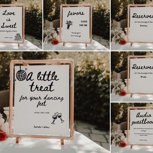 May include: A set of six wedding signs with black calligraphy on white backgrounds. The signs are displayed on wooden easels. The signs include "Love is Sweet", "Favors Please Take One", "Reserved for the Family of the Groom", "Reserved for the Family of the Bride", "A Little Treat for Your Dancing Feet", and "Audio Guestbook".