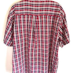 May include: A red, white, and blue plaid short-sleeved button-down shirt.
